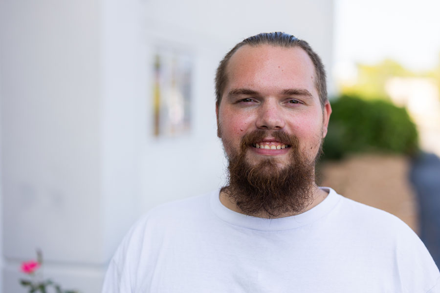 A man in a white shirt smiles at the camera