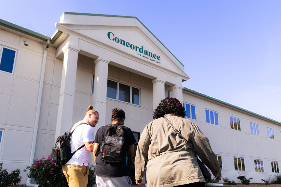 Three people walking into the concordance building