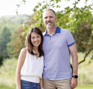 A man and woman stand next to each other smiling for the camera.