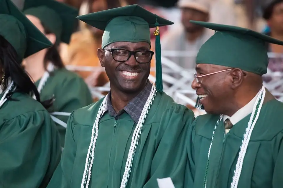 Two graduates smile at eachother.