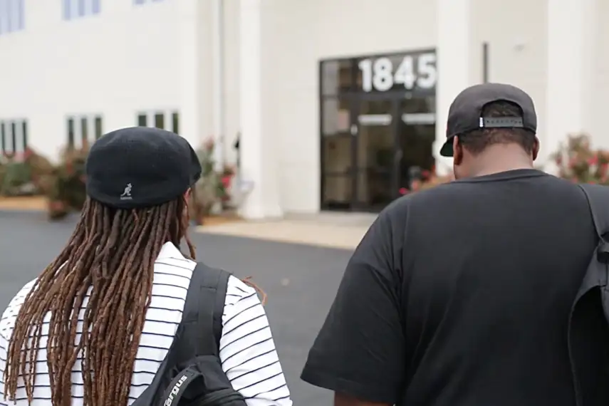 Two people walk toward the concordance building.