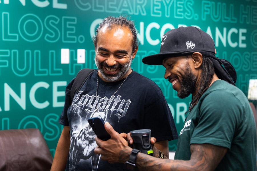 Two people smiling at one of the person's phone.