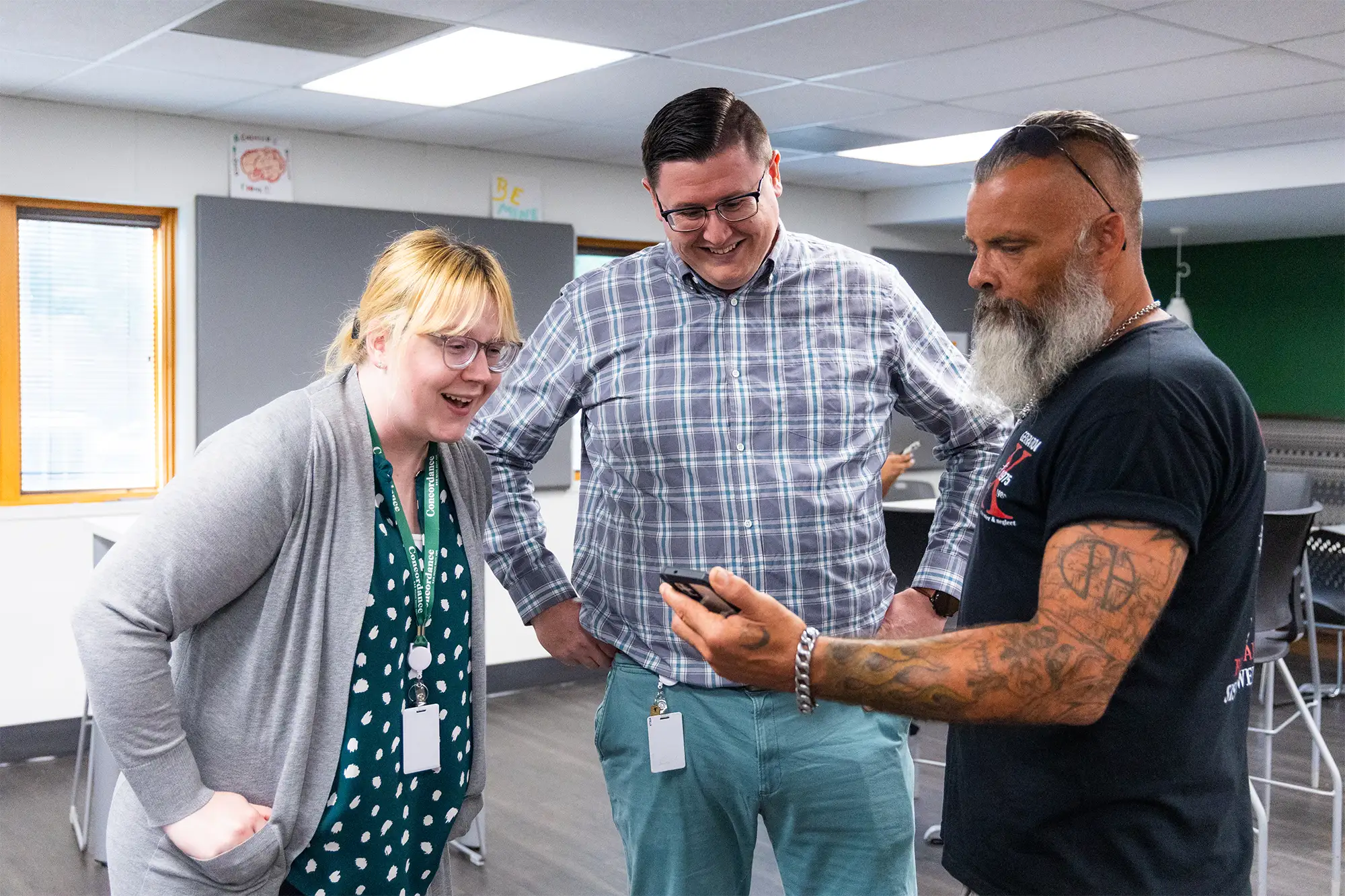Three people looking at a phone and smiling.