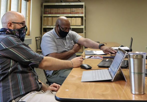 Two men sitting at a table looking at a laptop