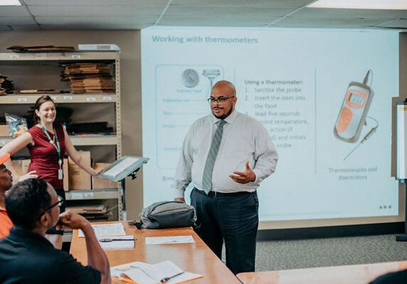 A man presenting in front of a class of people.